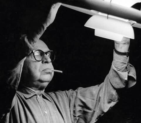 A portrait of Poul Henningsen inspecting his PH5 pendant lamp